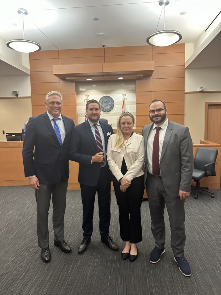 Michael stands with three other people in a courtroom.